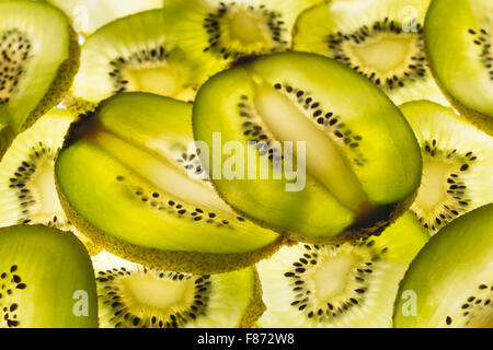 Esotica frutta kiwi retroilluminato in studio il taglio trasversale e longitudinale che mostra le sezioni interne di distribuzione di sementi intorno al nucleo centrale Foto Stock