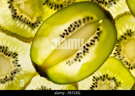 Esotica frutta kiwi retroilluminato in studio il taglio trasversale e longitudinale che mostra le sezioni interne di distribuzione di sementi intorno al nucleo centrale Foto Stock