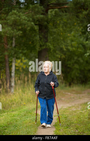 Donna matura impegnati in Nordic walking in schiera verde. Foto Stock