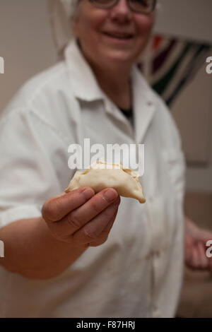 Home ucraino cook ha riempito appena impasto arrotolato con purè di patate per rendere tradizionali ucraine pirogis. Foto Stock