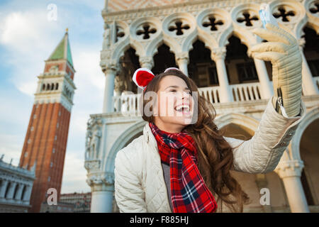 Stagione di Natale porta lo spirito di viaggio. Sorridente giovane donna turistica prendendo selfie spendendo vacanze di Natale a Venezia, Foto Stock