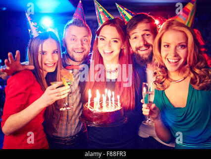 Amici di gioiosa con torta godendo di festa di compleanno Foto Stock