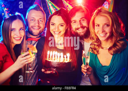 Amici di gioiosa con torta di compleanno il tifo nel night club Foto Stock