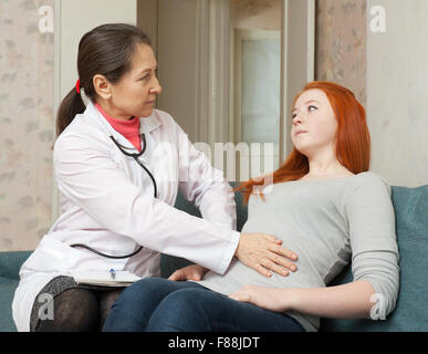 Medico tocca il ventre del paziente adolescente in interni Foto Stock