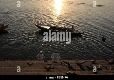 La mattina presto una barca passando attraverso due devoto sta facendo alcuni rituali per rendere omaggio alla Dea "Ganga' a Varanasi Ghat Foto Stock