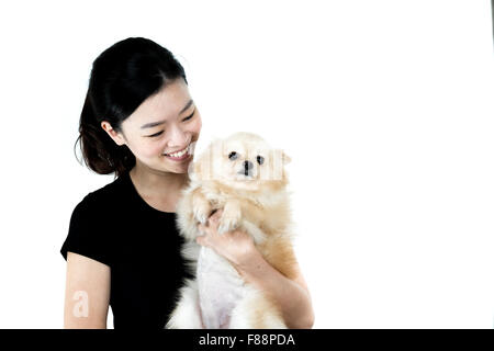 Carino ragazza asiatica holding cane di Pomerania, isolato su sfondo bianco Foto Stock