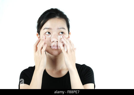 Carino ragazza asiatica di applicare la crema lozione sulla faccia, isolati su sfondo bianco Foto Stock