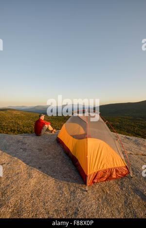 Escursionista su Roger battuta del vicino al tramonto, White Mountain National Forest, New Hampshire, con vista della gamma presidenziale all'orizzonte Foto Stock