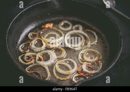 Friggere in padella nero bianco gli anelli di cipolla in olio Foto Stock