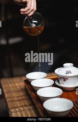 Le mani versando il tè in tazze Foto Stock