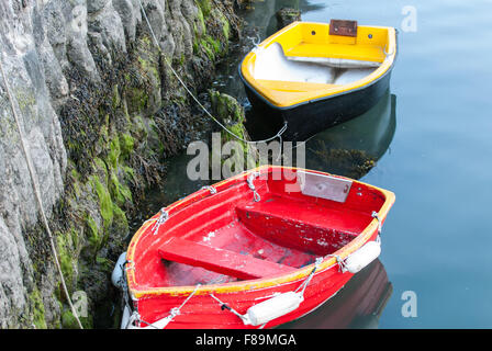 Due piccole barche a remi ormeggiate dalla parete del porto Foto Stock