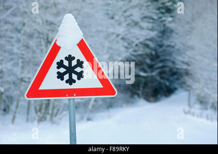 Cartello stradale avverte di neve e ghiaccio sulla strada Foto Stock