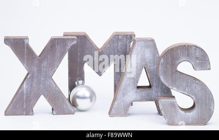 Lettere maiuscole formante la parola x-mas con argento palla di Natale su bianco Foto Stock