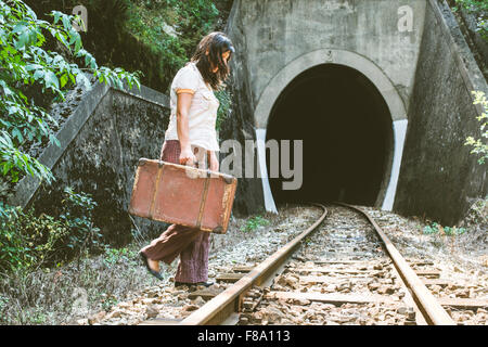 La donna a piedi su ferrovia con una valigia in mani. In stile vintage immagine Foto Stock