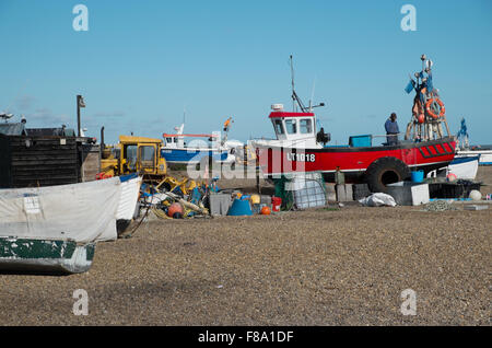 Un pescatore di riparazioni di rete su una barca da pesca sulla spiaggia di ciottoli di Aldeburgh Suffolk in Inghilterra Foto Stock