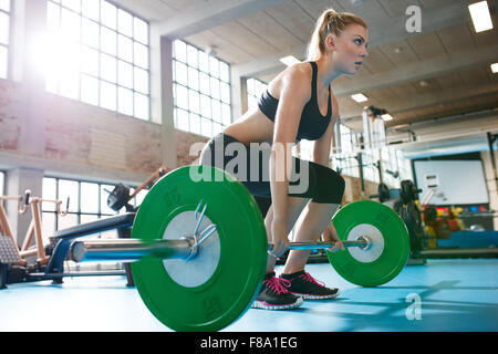 Muscolare donna caucasici in una palestra facendo pesanti esercizi di peso. Giovane donna fare sollevamento pesi al club della salute. Foto Stock