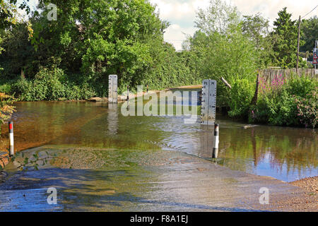 Un locale ford con un relativamente basso livello di acqua di circa dieci centimetri e l'acqua lentamente si muove in su di una posizione soleggiata e tranquilla giornata. Foto Stock