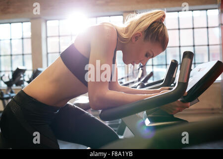 Donna prendendo pausa durante il ciclismo allenamento in palestra. Femmina su palestra bike facendo cardio esercizio. Foto Stock