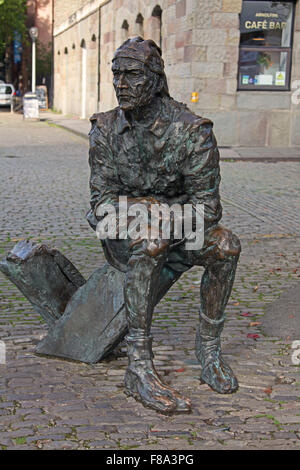 Una dimensione di vita uomo seduto su una roccia guardando vecchi e rilassata del peering attraverso le acque fusa in bronzo. Foto Stock