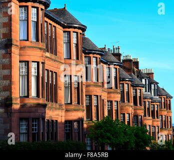 Fila di arenaria rossa casamenti vittoriano appartamenti su dowanhill street a glasgow west end cercando in discesa su una giornata di sole Foto Stock