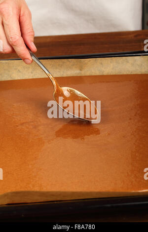 Livellamento di impasto sulla teglia. La produzione del cioccolato Brownie. Serie. Foto Stock