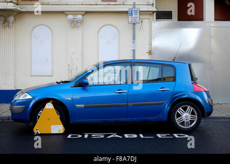 Ruota bloccata auto parcheggiate in sosta nella baia di disabili in un urbano area dello shopping England Regno Unito Foto Stock