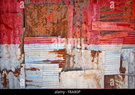 Un abstract immagine di sfondo della bandiera di Indonesia dipinta su di rusty ferro corrugato fogli sovrapposti per formare una parete Foto Stock