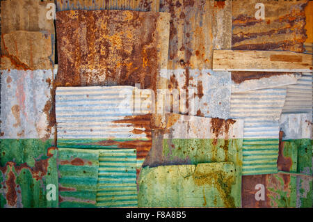 Un abstract immagine di sfondo di bandiera del Niger dipinta su di rusty ferro corrugato fogli sovrapposti per formare una parete di recinzione o Foto Stock