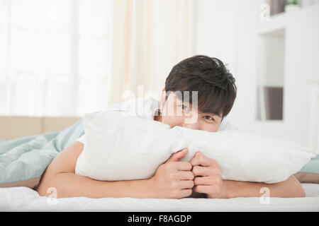 Uomo disteso sul suo viso sul cuscino nel letto e lo sguardo in avanti Foto Stock