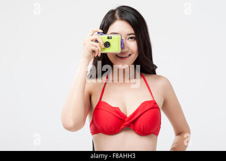 Asian woman in red bikini top prendendo una foto con una fotocamera Foto Stock