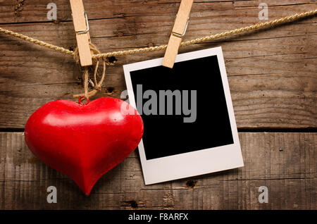 Cuore rosso forma e la vecchia foto su uno sfondo di legno Foto Stock