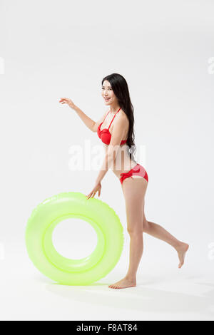 Donna sorridente in bikini in piedi su una gamba con un tubo Foto Stock