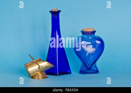 Due blu decorativo di bottiglie di vetro con una decorazione di oggetti di ottone su sfondo blu Foto Stock