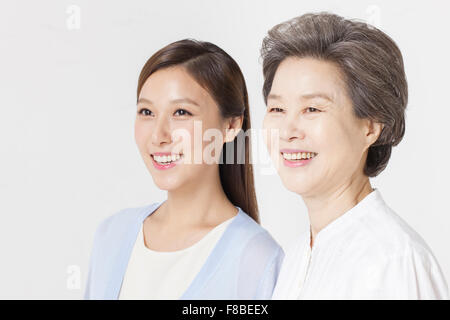 Madre e figlia guardando lo stesso lato e sorridente Foto Stock