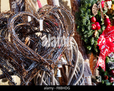 Tessuto di Willow le decorazioni di Natale in una forma di cuore e altre decorazioni tradizionali su una fase di stallo a Winchester Mercatino di Natale. Foto Stock