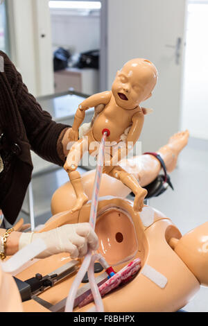 La levatrice degli studenti offrendo un manichino bambino da un adulto manichino, entrambi i manichini sono dotati di sensori, suono e altri dispositivi progettati per simulare molte delle condizioni reali di parto, Limoges, Francia. Foto Stock