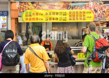 Turisti caucasica il campionamento street food - Hong Kong Foto Stock