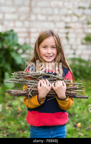 9-anno-vecchia ragazza la raccolta di legna da ardere. Foto Stock