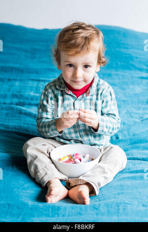 2 anno-vecchio ragazzo mangiando caramelle zuccherine. Foto Stock