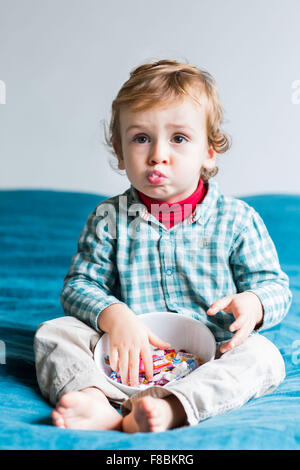 2 anno-vecchio ragazzo mangiando caramelle zuccherine. Foto Stock