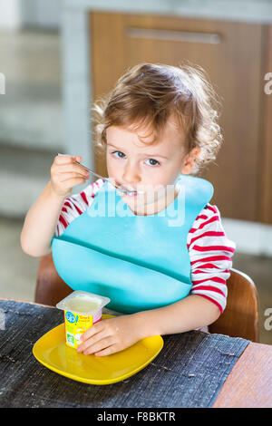 2 anno-vecchio ragazzo di mangiare uno yogurt. Foto Stock