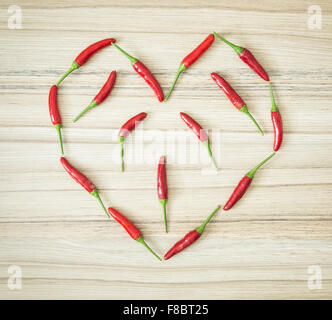 Chili Peppers sagomato nel bel cuore sullo sfondo di legno. Il giorno di San Valentino. Simbolo di amanti. Foto Stock