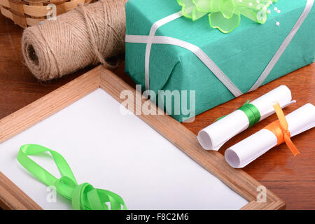 Blank photo frame con il regalo di Natale scatola, libro bianco con fiocco sul tavolo di legno. Foto Stock