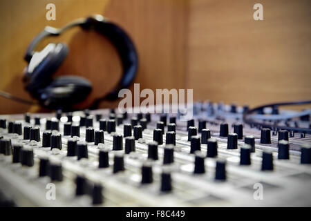 Manopole di regolazione dettaglio su un Professional mixer del suono con le cuffie in background Foto Stock
