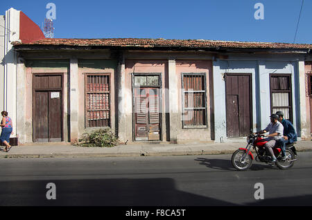 Un motociclo passa tipiche case cubane a Cienfuegos, sull'isola repubblica di Cuba Foto Stock