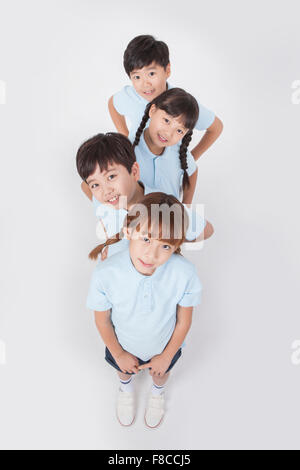 Elevato angolo di quattro scuole elementari in divise sportive allineate con le loro mani sulla loro vita e la loro inclinazione Foto Stock
