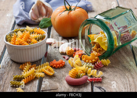 Vari tipi di pasta colorata su un sfondo di legno Foto Stock