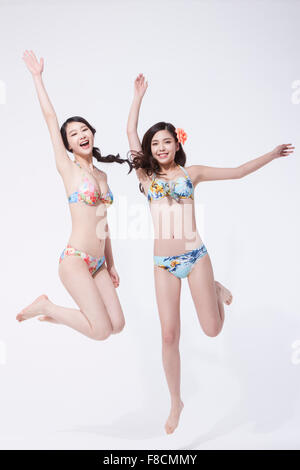 Due donne in bikini salta con le loro mani in alto Foto Stock
