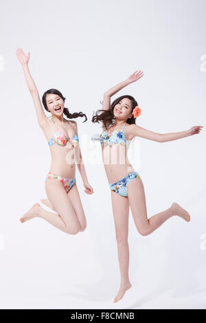 Due donne in bikini salta con le loro mani in alto Foto Stock