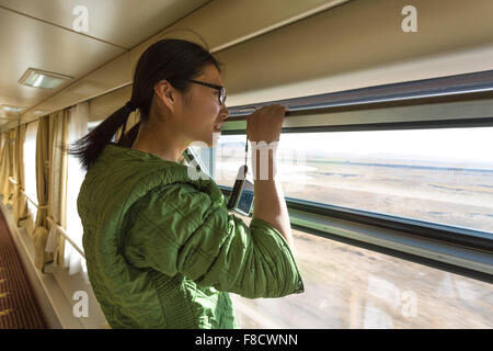 Il cinese giovane donna guardando da una finestra aperta in treno Foto Stock